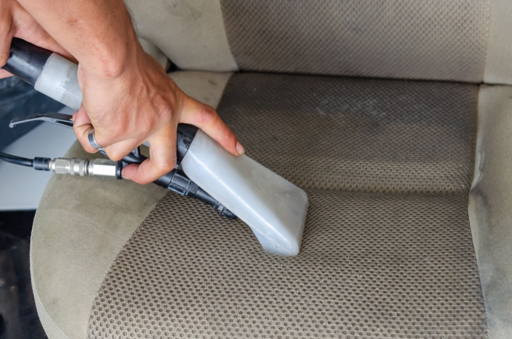 Upholstery extraction tool cleaning a fabric vehicle seat